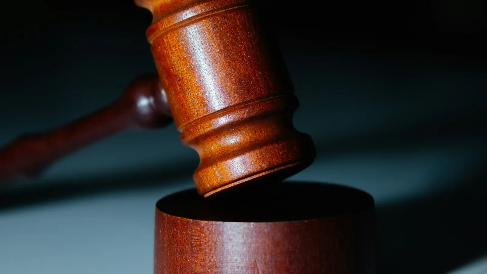 Wooden gavel resting on its sound block against a dark background.