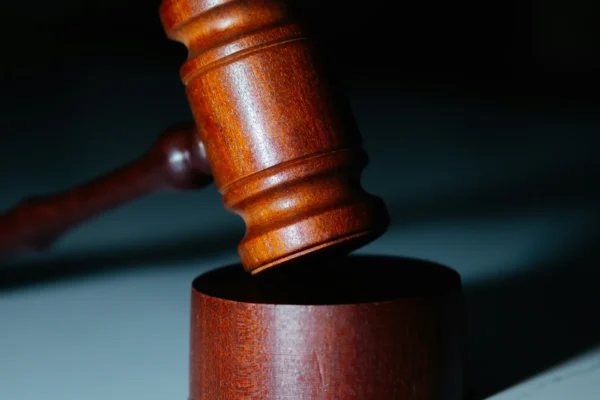 Wooden gavel resting on its sound block against a dark background.